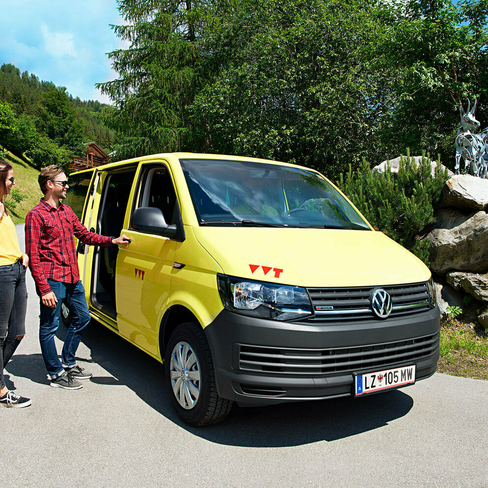 Auf dem Bus sind zwei Wanderer zu sehen, die gerade in das gelbe Wanderbus einsteigen