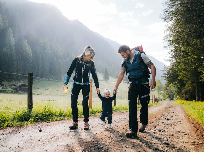 Eine Mann und eine Frau mit ihrem kleinen Kind dazwischen wandert im Kristeinertal.
