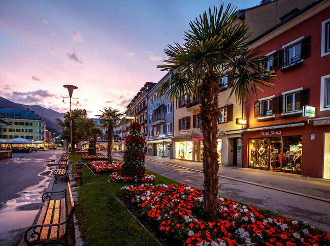 Die Blumenbeete und Bänke am Lienzer Hauptplatz in der Abenddämmerung. Der Himmel färbt sich leicht rosa.