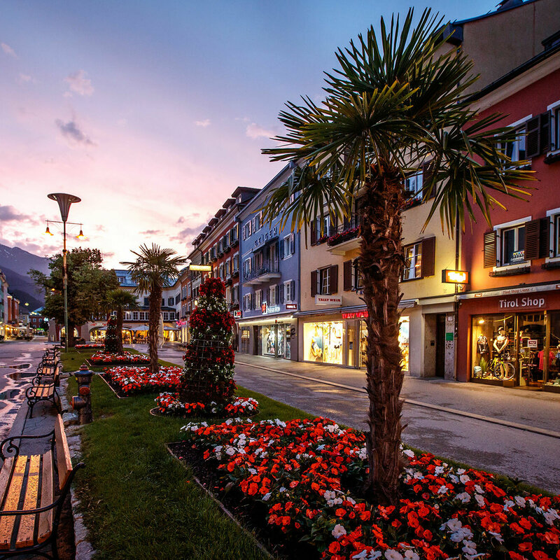 Die Blumenbeete und Bänke am Lienzer Hauptplatz in der Abenddämmerung. Der Himmel färbt sich leicht rosa.