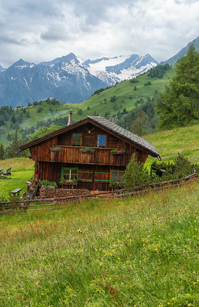 Die urige Gottschaunalm umringt von saftigen Wiesen, mit beeindruckender Bergkulisse im Hintergrund.