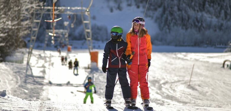 Kinder werden der Reihe nach vom Schlepplift an den Startpunkt der Pistenabfahrt gebracht.