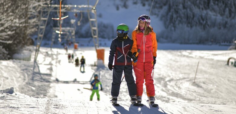 Kinder werden der Reihe nach vom Schlepplift an den Startpunkt der Pistenabfahrt gebracht.