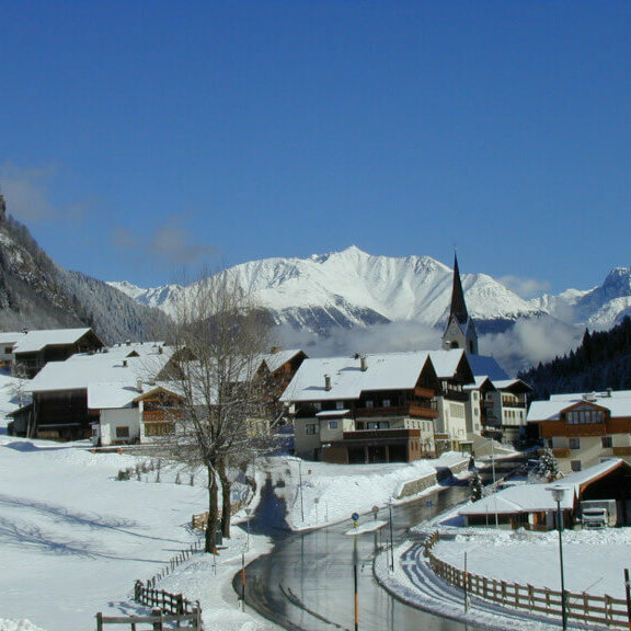 Ein Blick auf das verschneite Hopfgarten i. D., im Hintergrund sind die Kirche und die Berge zu sehen.
