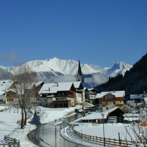 Ein Blick auf das verschneite Hopfgarten i. D., im Hintergrund sind die Kirche und die Berge zu sehen.