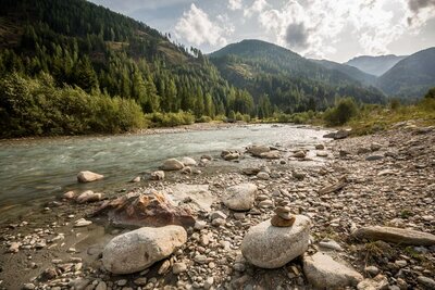 Die Bachaufweitung Schwarzach in Maria Hilf in St. Jakob im Defereggental. Kleiner Steinhaufen am Ufer der Schwarzach.