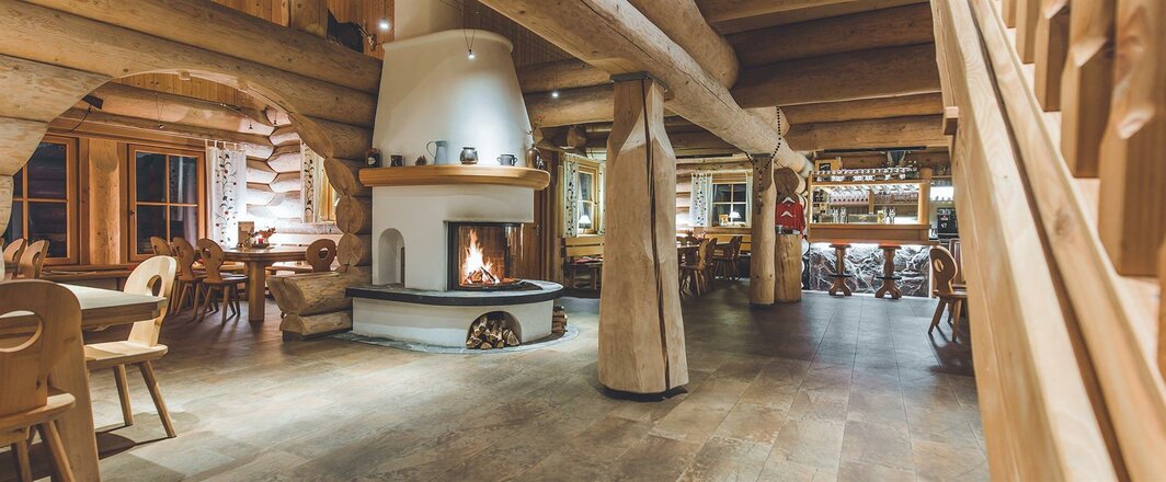 Der Gastraum der Nilljochhütte ist mit viel Holz gestaltet und vermittelt eine gemütliche Hüttenatmosphäre. Im Mittelpunkt steht ein Kamin mit offenem Feuer, um den Tische und Sitzgelegenheiten angeordnet sind. Massive Holzbalken, Holzmöbel und große Fenster prägen den Innenraum.