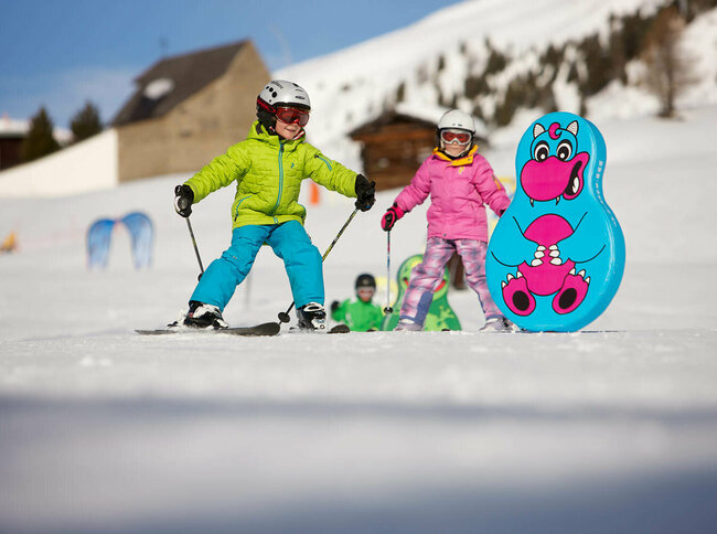 Kinder fahren am Zettersfeld in Lienz auf ihren Skier durch lustige Figuren