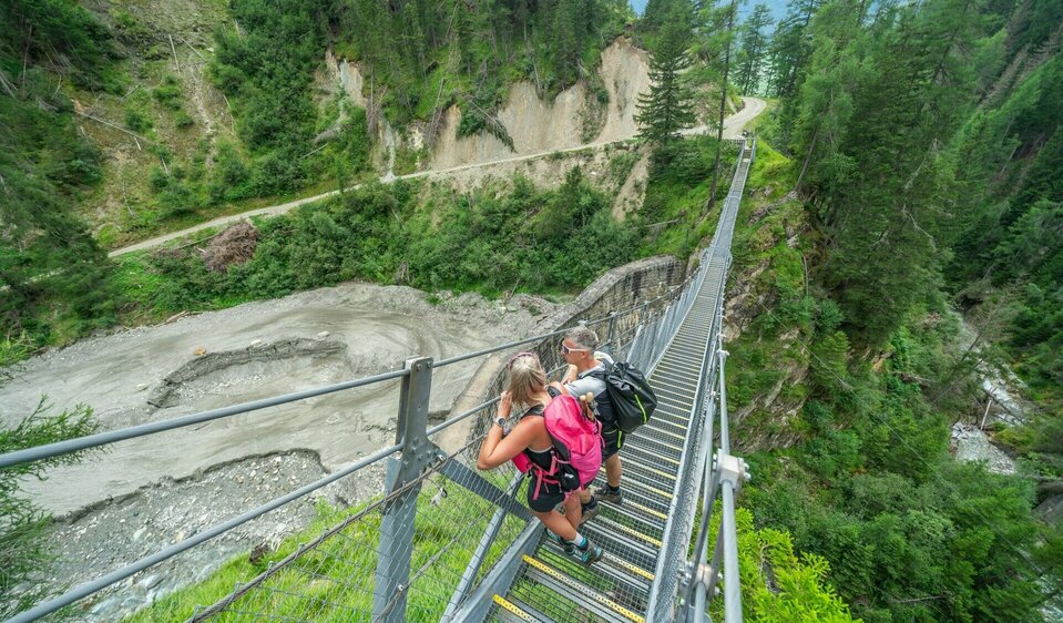 Wanderer überqueren Hängebrücke auf Etappe 5 der Glocknerkrone in Osttirol nahe Kals am Großglockner beim Weitwandern.
