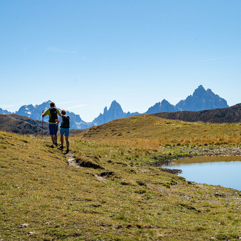 zwei Wanderer auf dem Herz-Ass-Wanderweg Villgratental bei einem kleinen Bergsee