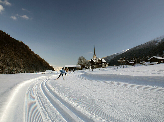Langlaufen auf der perfekt gespurten Loipe im Defereggental mit dem Ort im Hintergrund