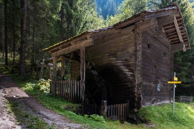 Die aus Holz gebaute Böckn Mühle in Hopfgarten i. D., welche neben einem Wanderweg im Wald gelegen ist.