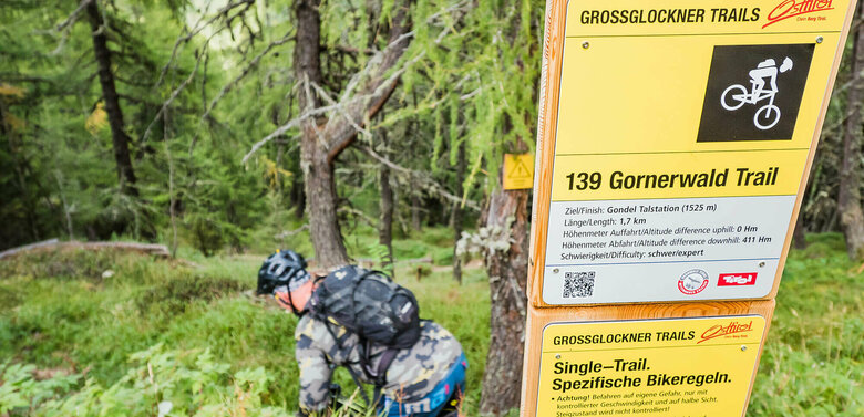 Mountainbiker bei einem Hinweisschild betreffend der Verhaltensreglen beim Biken
