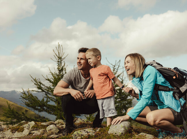 Eine junge Familie schaut gespannt in die Ferne auf der Kindermeile Obertilliach