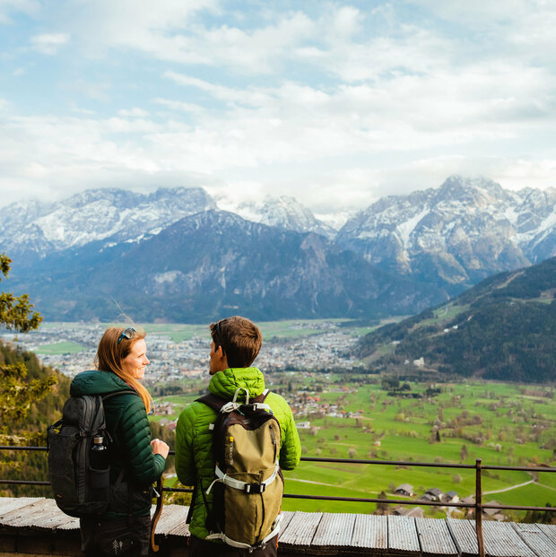 Zwei Wanderer genießen den Ausblick vom Helenenkirchl auf die Stadt Lienz und die noch zum Teil schneebedeckten Gipfel der Lienzer Dolomiten.