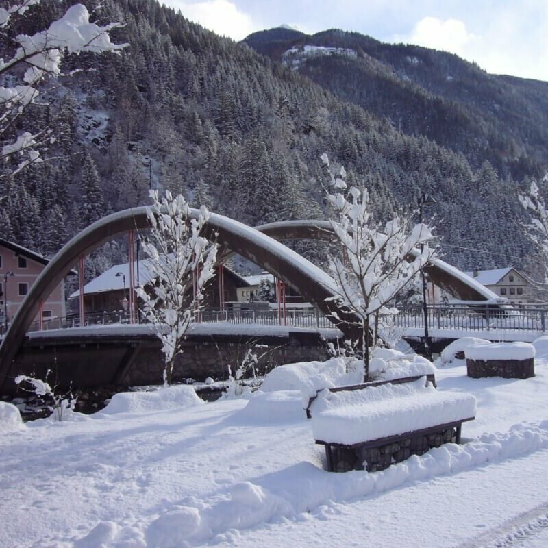 Die Brücke in St. Johann mit viel Neuschnee und einem Wald im Hintergrund.