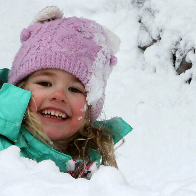 Ein Kind spielt fröhlich im frischen Schnee
