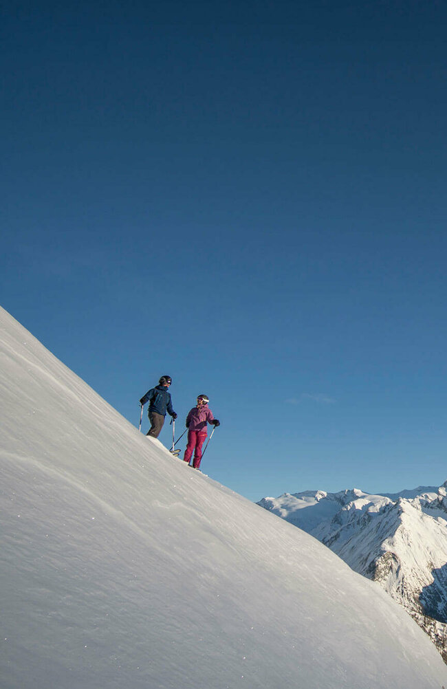 Blick aus der Ferne auf zwei Freerider im Bergpanorama des Großglockner Resort Kals Matrei
