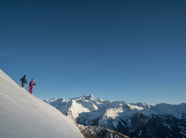 Blick aus der Ferne auf zwei Freerider im Bergpanorama des Großglockner Resort Kals Matrei