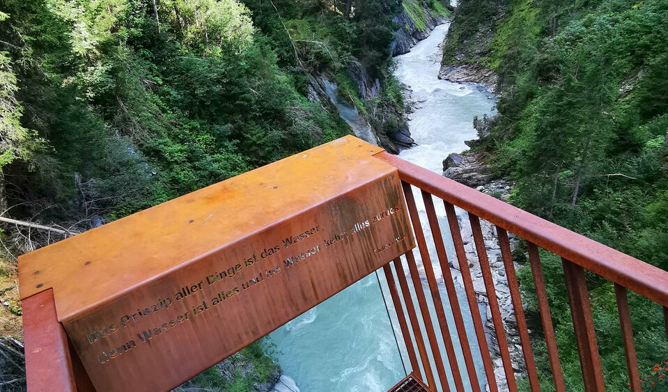 Eine Metall-Plattform bei der Iselschlucht mit Ausblick auf das fließende Wasser zwischen den Bäumen.