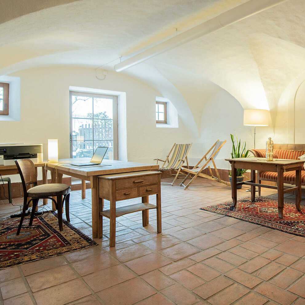 Coworking Raum im Kesslerstadel mit Arbeitstischen, Drucker und für Pausen stehen zwei Liegestühle bereit.
