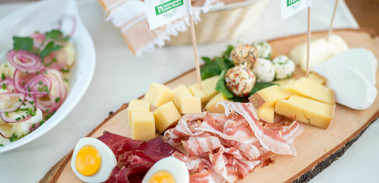 Brettljause mit verschiedenen Käsesorten in Würfel geschnitten, feinen Speck- und Henkelescheiben und hartgekochten Eiern.