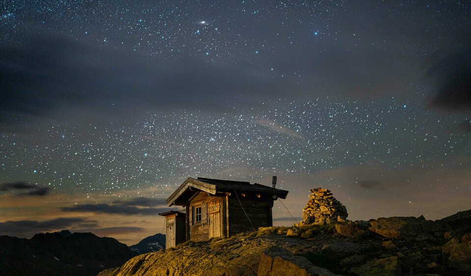 Sternenhimmel in Osttirol über einer urigen Holz-Hütte.
