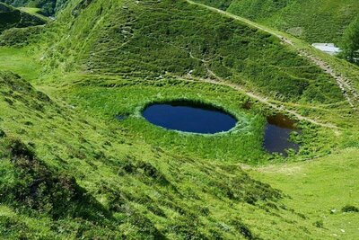 Der Wasserkrafort Pfauenauge hinter den Jagdhausalmen in St. Jakob i. D.. Ein kreisrunder, kleiner Bergsee welcher sich mit seiner kräftig-blauen Farbe aus der saftig-grünen Umgebung deutlich heraushebt.