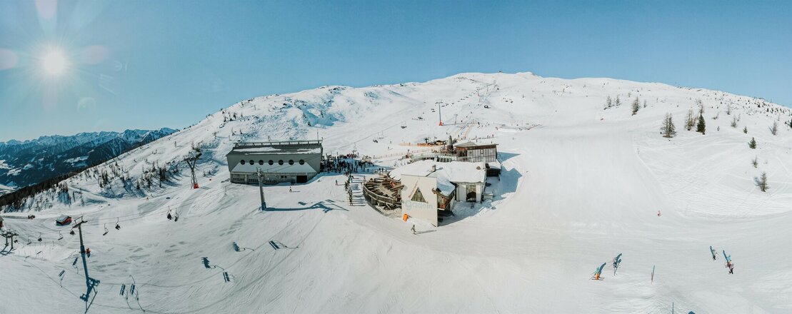 Blick aus Vogelperspektive auf das Bergrestaurant Gadein im Skigebiet Thurntaler an einem herrlichen Wintertag.