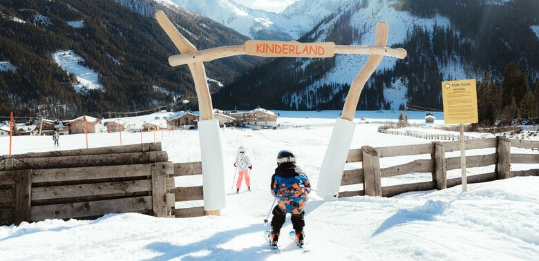 Ein Kind passiert auf Ski den Eingang ins Kinderland im Familienskigebiet Golzentipp in Obertilliach.