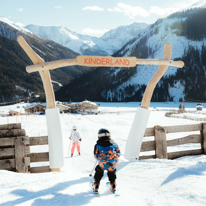 Ein Kind passiert auf Ski den Eingang ins Kinderland im Familienskigebiet Golzentipp in Obertilliach.