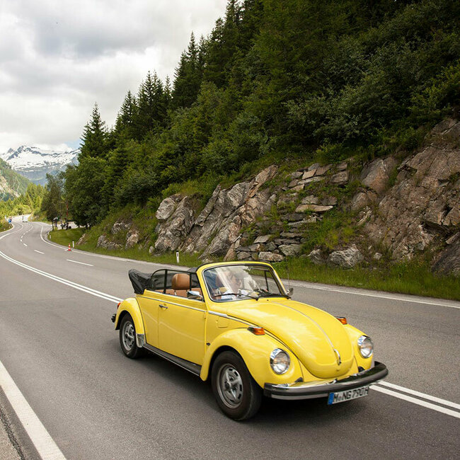 Ein gelbes Oldtimer-Cabriolet fährt auf der Felbertauernstraße, gefolgt von einem silbernen Cabriolet.