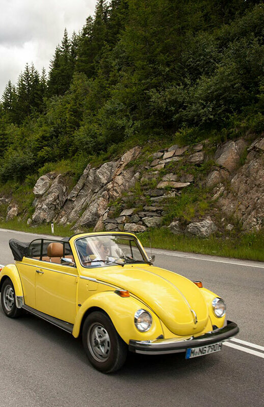 Ein gelbes Oldtimer-Cabriolet fährt auf der Felbertauernstraße, gefolgt von einem silbernen Cabriolet.