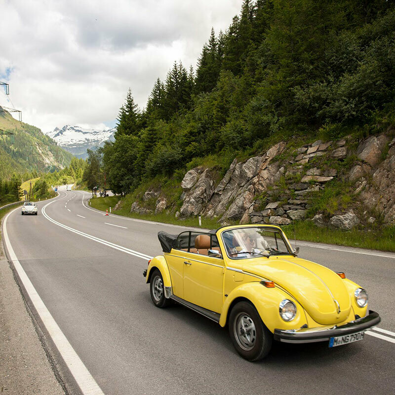 Ein gelbes Oldtimer-Cabriolet fährt auf der Felbertauernstraße, gefolgt von einem silbernen Cabriolet.