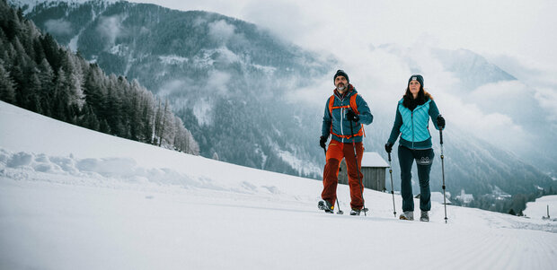 Ein Pärchen wandert auf perfekt präparierten Winterwanderwegen durch Osttirols Winterlandschaft.