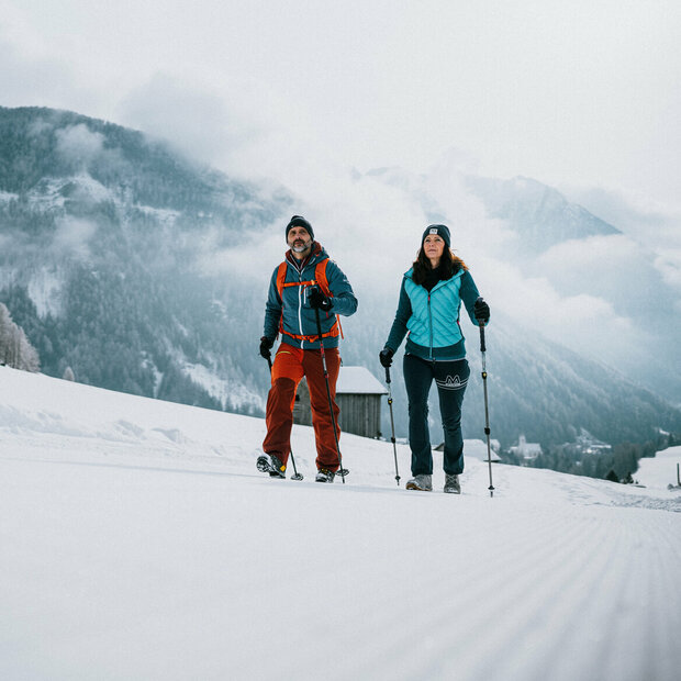 Ein Pärchen wandert auf perfekt präparierten Winterwanderwegen durch Osttirols Winterlandschaft.