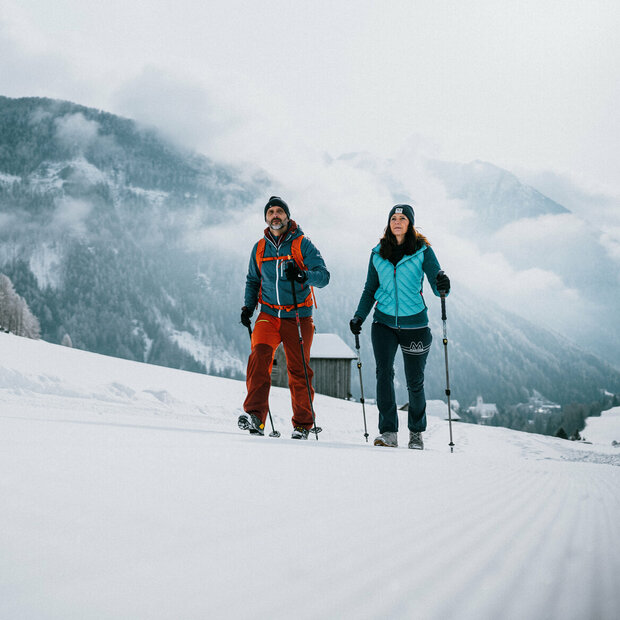 Ein Pärchen wandert auf perfekt präparierten Winterwanderwegen durch Osttirols Winterlandschaft.
