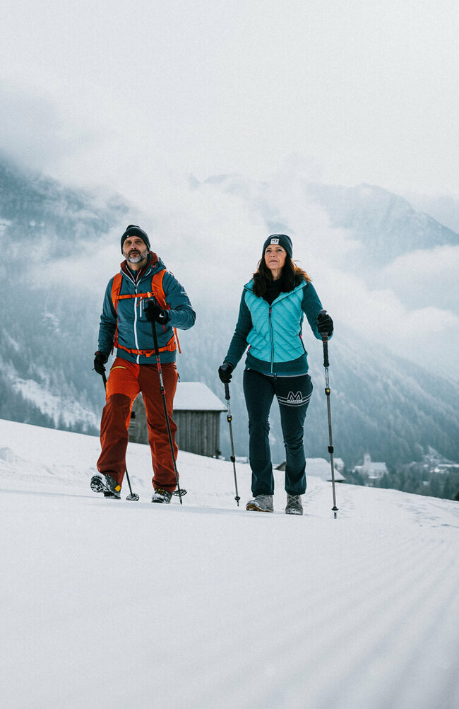 Ein Pärchen wandert auf perfekt präparierten Winterwanderwegen durch Osttirols Winterlandschaft.