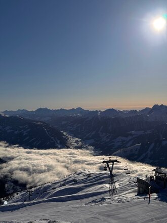 Eine malerische Berglandschaft mit schneebedeckten Hängen und einer Wolkendecke im Tal.