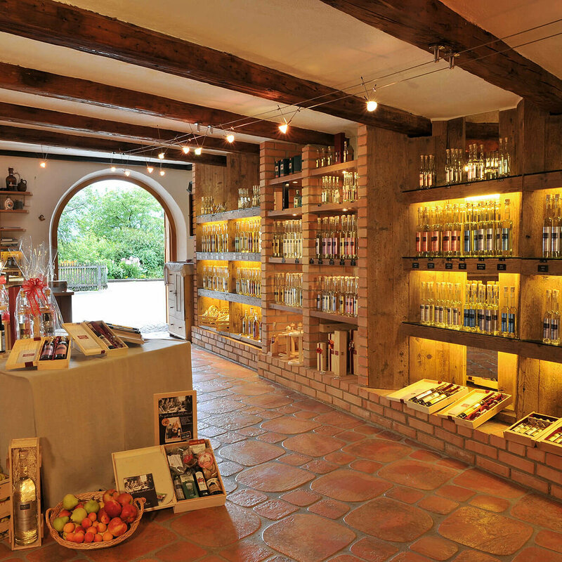 Innenansicht des Hofladens der Schnapsbrennerei Kuenz in Dölsach mit vielen verschiedenen Schnäpsen und Likören sowie Äpfel.