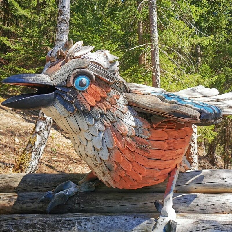 Eine große, bunte Holzfigur eines Vogels auf dem Vogelerlebnisweg.
