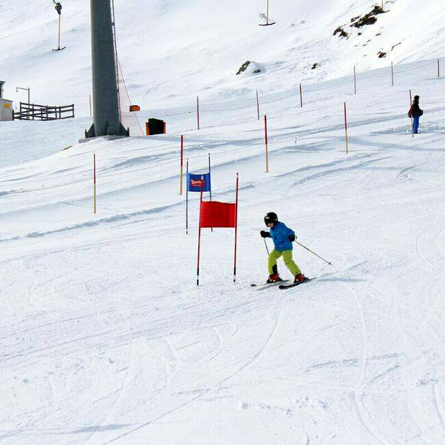 Kind fährt auf den Skier durch rote und blaue Tore.