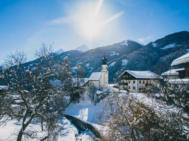 Blick auf die Kirche in Virgen im Winter bei strahlendem Sonnenschein.