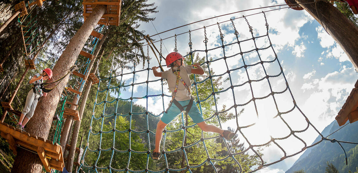Drei Kinder beim Klettern über Hindernisse im Hochseilgarten Galitzenklamm