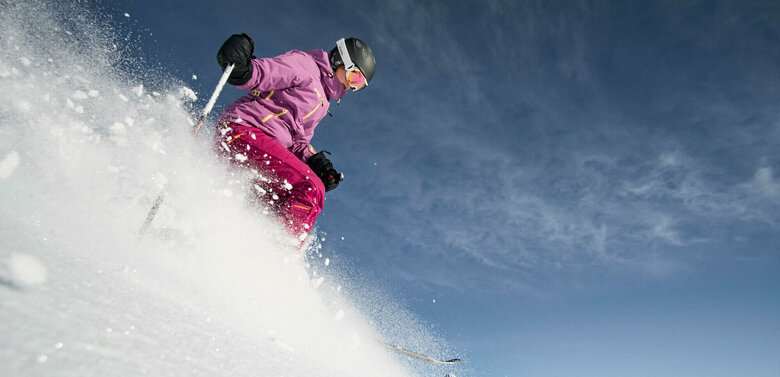Eine pink-lila gekleidete Freeriderinn im Pulverschnee im Großglockner Resort in Kals-Matrei.