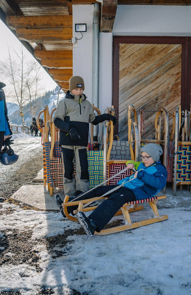 Eine Familie in bunten Skianzügen beim Rodelverleih in Außervillgraten in Osttirol.