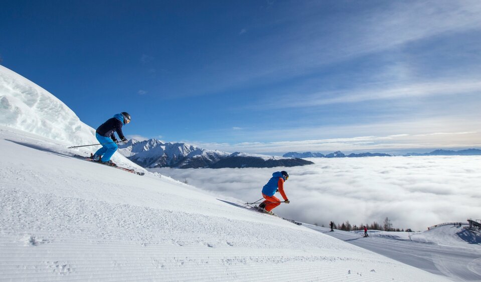 Zwei Skifahrer:innen bei der Abfahrt im Skigebiet Sillian 