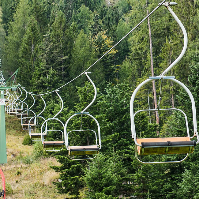 Zwei Liftfahrer drehen sich während der Fahrt mit dem Sessellift der Lienzer Bergbahn Hochstein zur Kamera um.