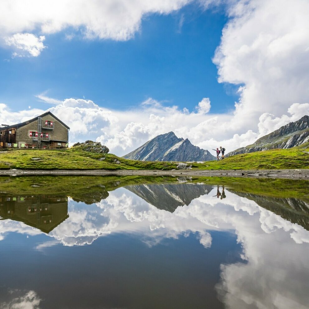 Die Sudetendeutsche Hütte auf der ersten Etappe der Glocknerkrone in Osttirol. Der See reflektiert die Berge der Granatspitzgruppe.