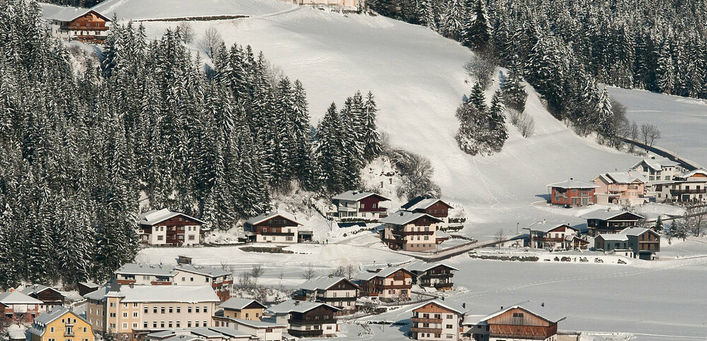 Ortsansicht Strassen von oben mit der markanten Pfarrkirche bei tief winterlicher Umgebung.
